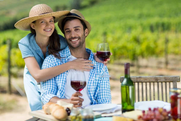 Young couple holding red wine at table — Stock Photo, Image