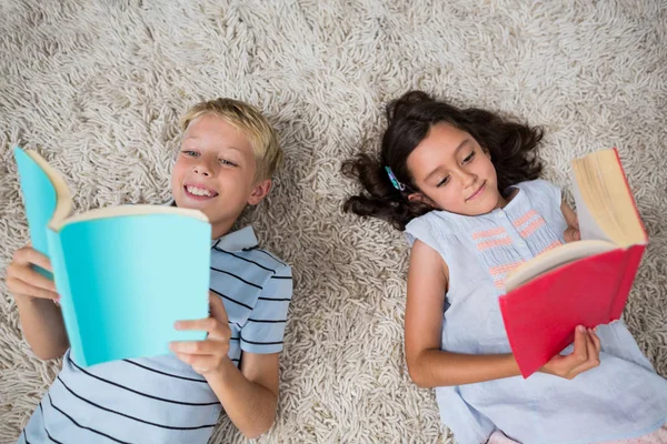 Syskonen liggande på matta och läsa bok — Stockfoto