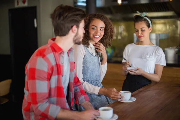 Vrouw vriend kijken terwijl het plaatsen van de bestelling aan serveerster — Stockfoto