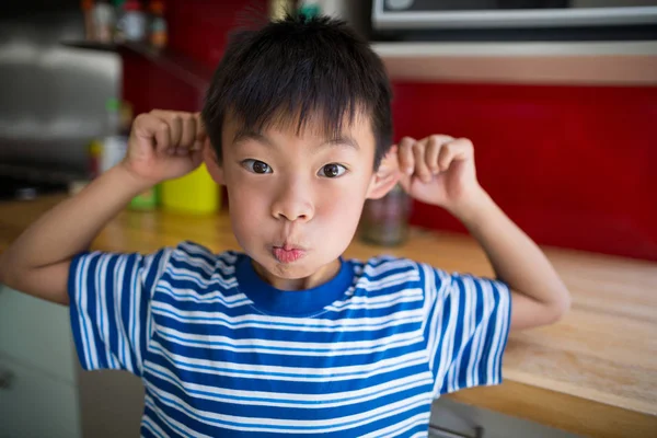 Мальчик делает смешное лицо на кухне — стоковое фото