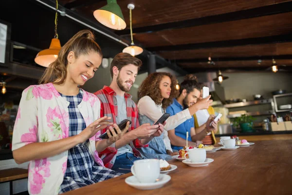 Vänner med sina mobiltelefoner i restaurang — Stockfoto