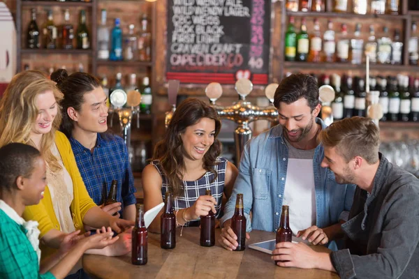 Vrienden met bierflesjes permanent rond tafel — Stockfoto