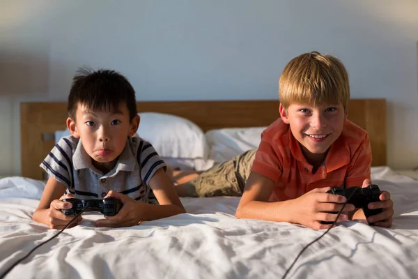 Siblings playing video game on bed — Stock Photo, Image