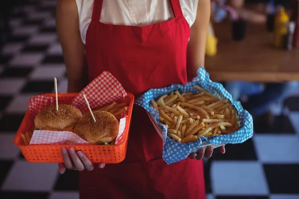 Офіціантка тримає бургер і картоплю фрі в лотку — стокове фото