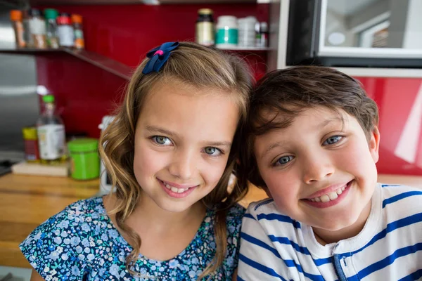 Broers en zussen glimlachend in de camera in de keuken — Stockfoto