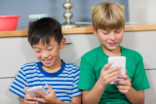 Hermanos usando teléfono móvil en la sala de estar —  Fotos de Stock