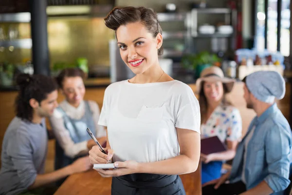 Waitress standing by customers in restaurant — Stock Photo, Image