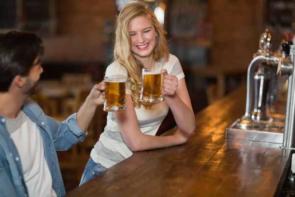 Kvinde ristning øl med mandlige ven på pub - Stock-foto