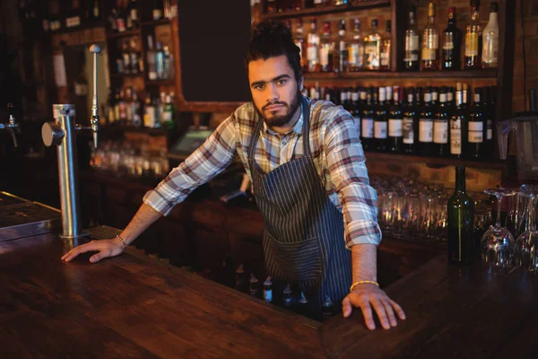 Waiter leaning at counter in pub — Stock Photo, Image