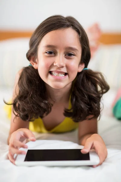 Mosolygó lány az ágyon, digitális tabletta — Stock Fotó