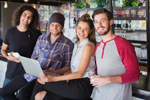 Smiling friends using laptop in restaurant — Stock Photo, Image