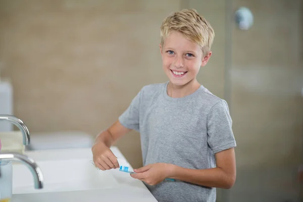 Niño poniendo pasta de dientes en el cepillo en el baño — Foto de Stock