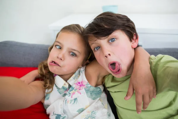 Geschwister ziehen lustige Gesichter im Wohnzimmer — Stockfoto