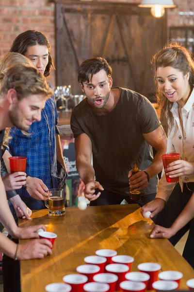 Amici che guardano la palla mentre l'uomo gioca a birra pong — Foto Stock