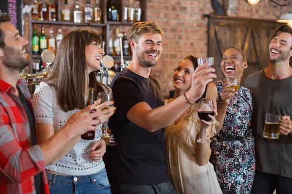 Amigos riendo juntos mientras celebran bebidas —  Fotos de Stock