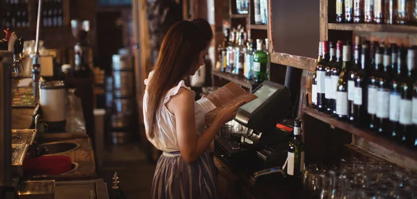 Female bar tender looking at menu — Stock Photo, Image