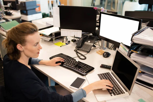 Businesswoman typing on laptop while using desktop pc — Stock Photo, Image