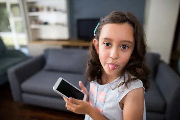 Girl sticking out tongue while holding phone — Stock Photo, Image