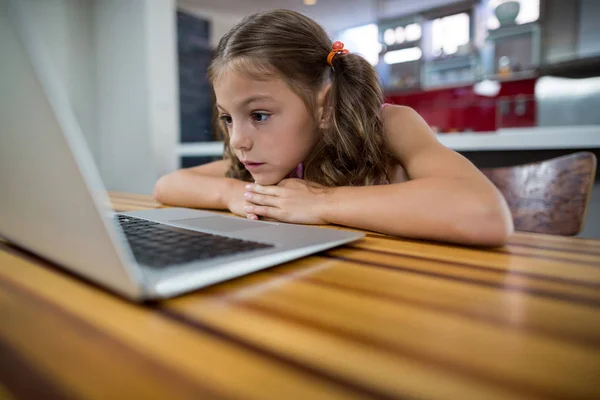 Menina olhando para laptop na cozinha — Fotografia de Stock