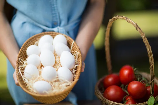 Woman holding eggs by tomatoes — Stock Photo, Image