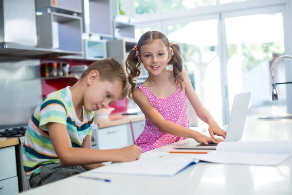 Pojken gör sina läxor medan flickan med laptop — Stockfoto