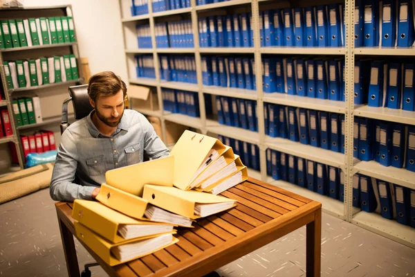 Empresário olhando para pilha de arquivos na mesa — Fotografia de Stock