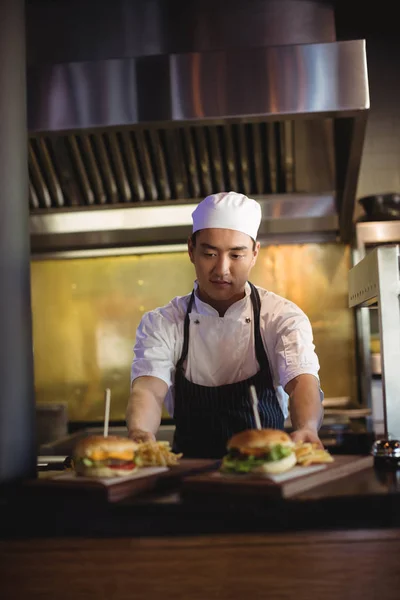 Chef menempatkan nampan dengan kentang goreng dan burger — Stok Foto