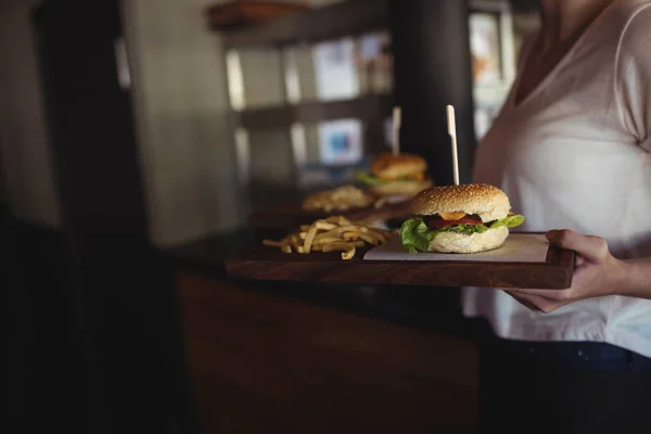 Mujer llevando hamburguesa y papas fritas en una bandeja —  Fotos de Stock