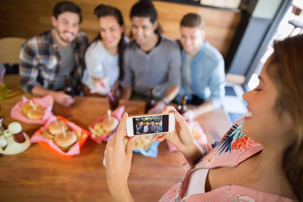 Mujer fotografiando amigos en restaurante — Foto de Stock