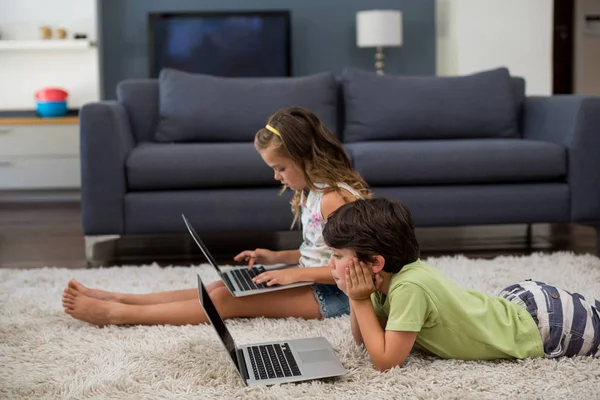 Syskon med laptop i vardagsrum — Stockfoto