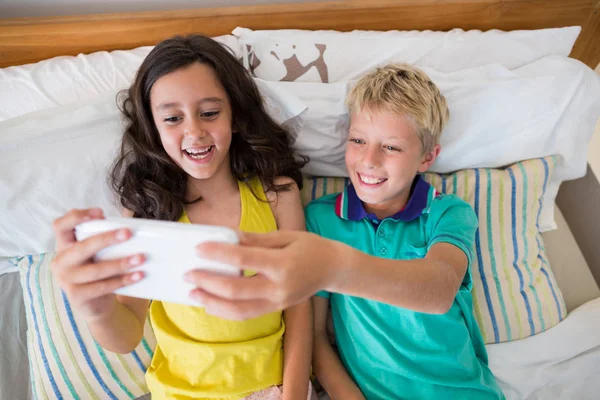 Siblings taking selfie on phone in bedroom — Stock Photo, Image