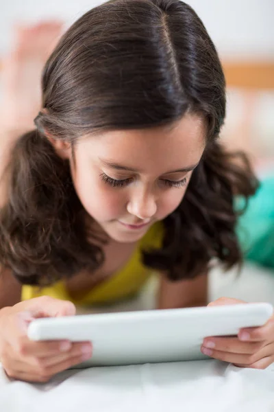 Mädchen benutzt digitales Tablet auf Bett im Schlafzimmer — Stockfoto