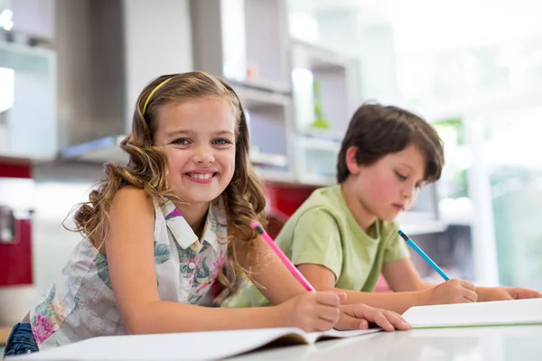 Siblings doing homework in kitchen — Stock Photo, Image