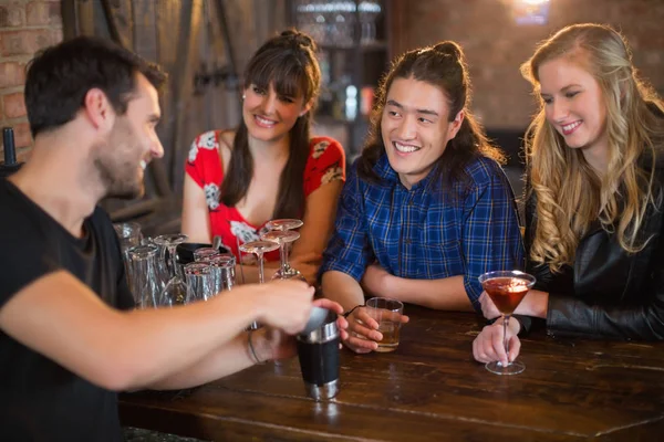 Amigos olhando para barman fazendo bebidas em pub — Fotografia de Stock