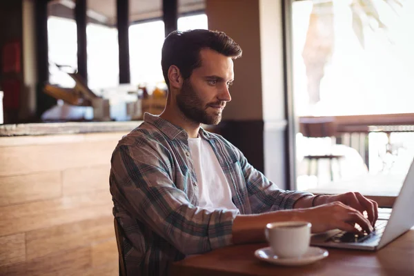 Mann benutzt Laptop beim Kaffeetrinken — Stockfoto