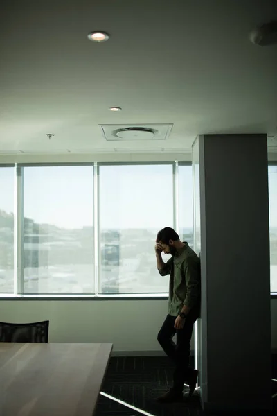 Worried businessman standing by window — Stock Photo, Image