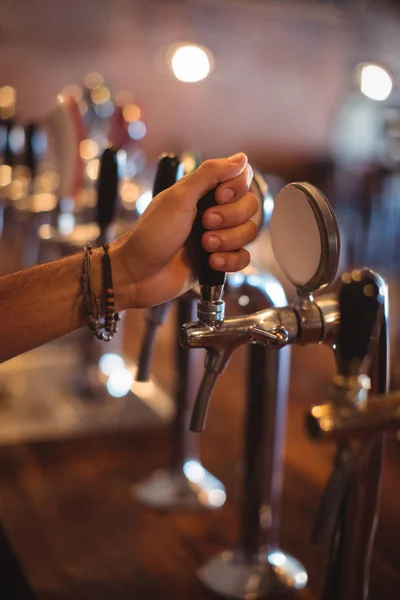 Manos de camarero usando el grifo de cerveza en el pub — Foto de Stock