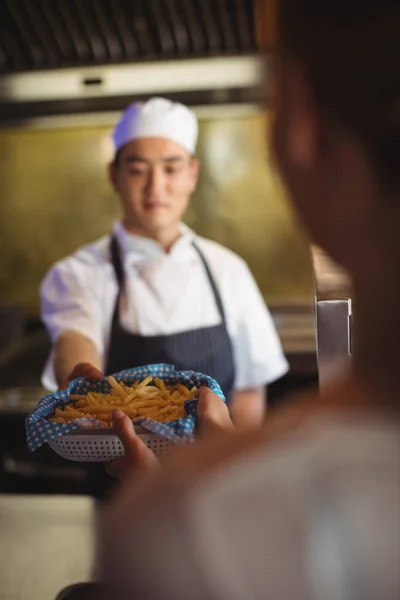 Chef pasando bandeja con papas fritas a camarera —  Fotos de Stock