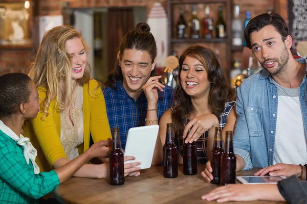 Amigos com garrafas de cerveja usando tablet digital — Fotografia de Stock