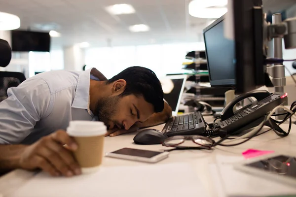 Уставший бизнесмен спит за настольными компьютерами — стоковое фото