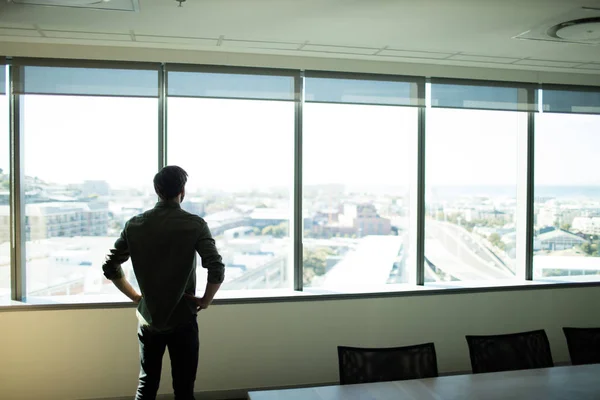 Uomo d'affari guardando attraverso la finestra sul posto di lavoro — Foto Stock