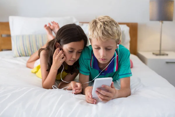 Siblings listening to music while using phone — Stock Photo, Image