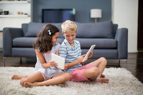 Frères et sœurs assis sur un tapis et utilisant une tablette — Photo