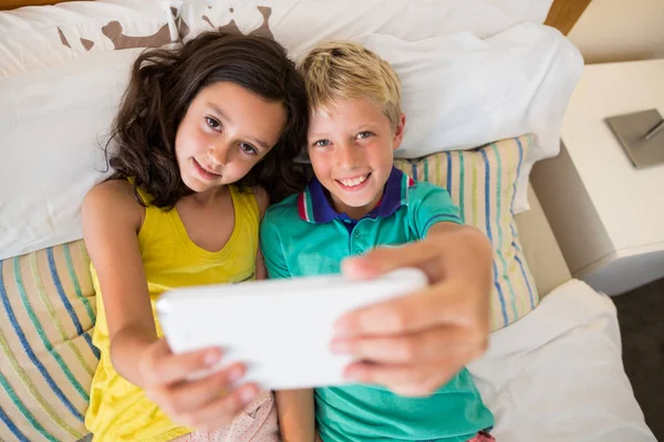 Irmãos tomando selfie no telefone no quarto — Fotografia de Stock