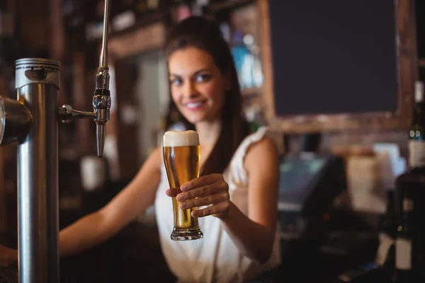 Female bar tender holding glass of beer — Stock Photo, Image