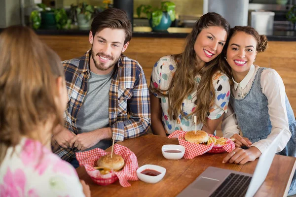 Amigos alegres comiendo hamburguesa en el restaurante — Foto de Stock