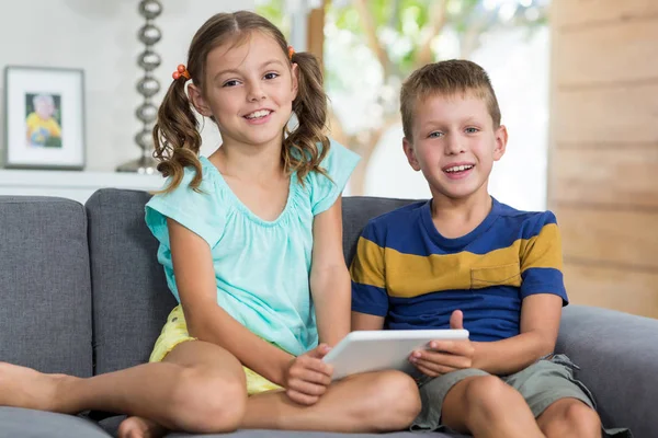 Siblings with tablet on sofa in living room — Stock Photo, Image
