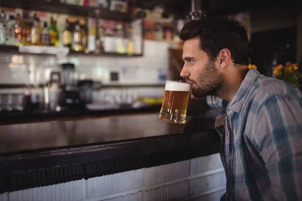 Человек пьет пиво за прилавком — стоковое фото
