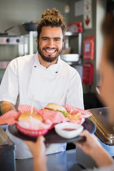 Chef feliz dando hamburguesas a la camarera — Foto de Stock