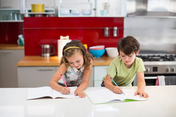 Братья и сестры делают домашнее задание на кухне — стоковое фото
